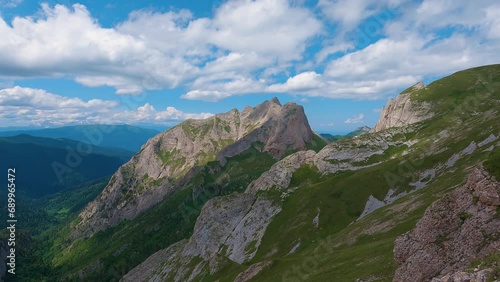 Panoramic mountain landscape with green slopes and steep cliffs. Blue cloudy sky over the mountains. Hiking in the mountains photo