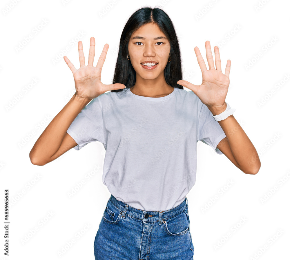 Beautiful young asian woman wearing casual white t shirt showing and pointing up with fingers number ten while smiling confident and happy. Beautiful young asian woman wearing casual white t shirt showing and pointing up with fingers number ten while smiling confident and happy.