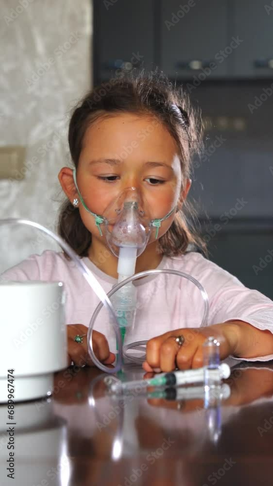 Unhappy little girl, unwell and wearing a medicine mask. Medical equipment in use for inhalation therapy during pneumonia. Vertical video. Unhappy little girl, unwell and wearing a medicine mask. Medical equipment in use for inhalation therapy during pneumonia. Vertical video.