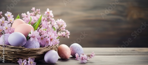 Pastel Easter eggs in a basket with flowers on a wooden table.