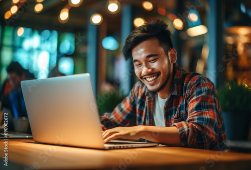 Attractive young asian man sitting in front of a laptop smiling