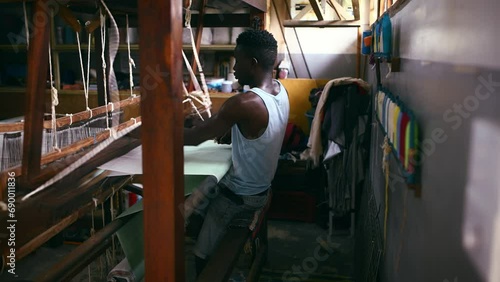 Man, floor treadle loom and weaving for production at clothing factory, manufacture and craftsmanship. Black male person, warehouse and thread or cotton industry, wool and fabric designer or textiles
