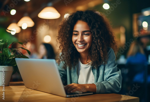 Attractive young hispanic woman sitting in front of a laptop smiling