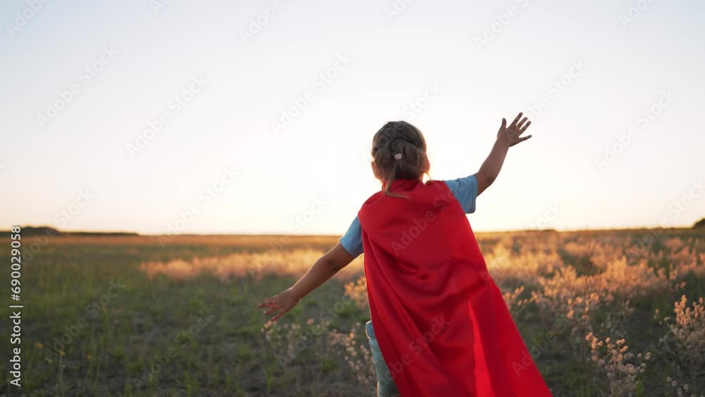 Dream of freedom. Girl superhero in park at sunset. Child winner hero plays in nature. An active girl in red superhero costume runs in park.Childhood dream of victory and heroism.Happy family concept Dream of freedom. Girl superhero in park at sunset. Child winner hero plays in nature. An active girl in red superhero costume runs in park.Childhood dream of victory and heroism.Happy family concept