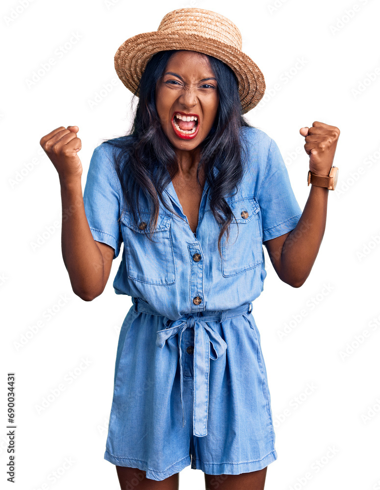Young indian girl wearing summer hat angry and mad raising fists frustrated and furious while shouting with anger. rage and aggressive concept. Young indian girl wearing summer hat angry and mad raising fists frustrated and furious while shouting with anger. rage and aggressive concept.