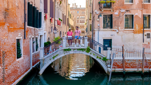 a couple of men and women on a city trip in Venice Italy sitting above a bridge at the canals of Venice, during a city trip in summer in Europe © Fokke Baarssen