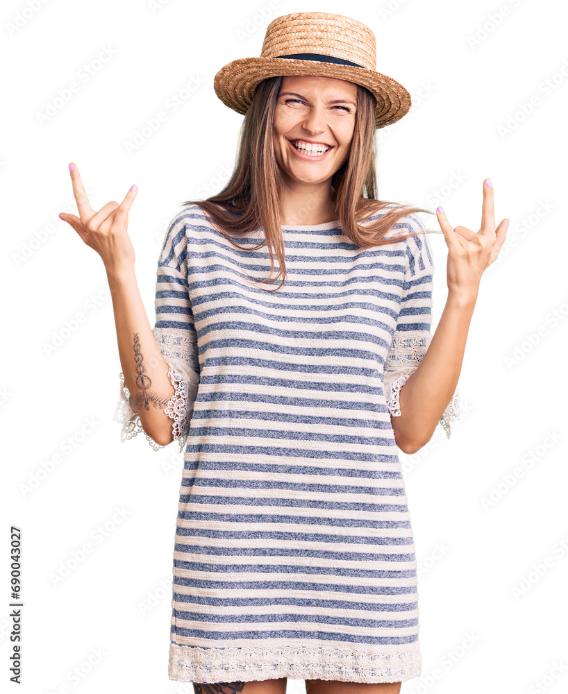 Beautiful caucasian woman wearing summer hat shouting with crazy expression doing rock symbol with hands up. music star. heavy concept.