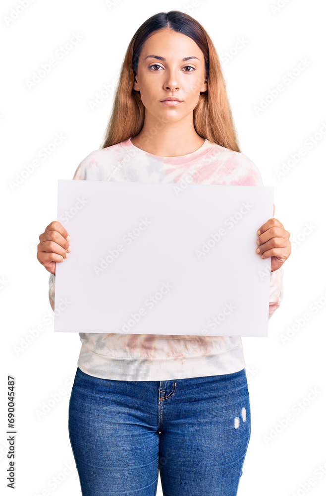 Beautiful young woman holding blank empty banner thinking attitude and sober expression looking self confident Beautiful young woman holding blank empty banner thinking attitude and sober expression looking self confident