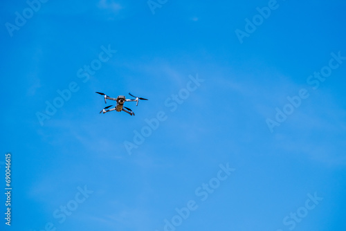 drone flying against a clear blue sky, symbolizing modern technology and surveillance.