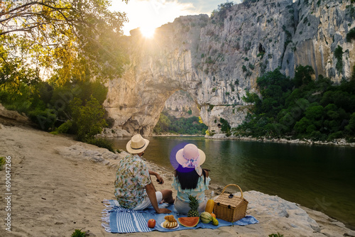 couple on vacation in the Ardeche France, view of Natural arch in Vallon Pont d'Arc in Ardeche canyon in France Europe Rhone Alps Dordogne, men and woman at the beach by the river photo