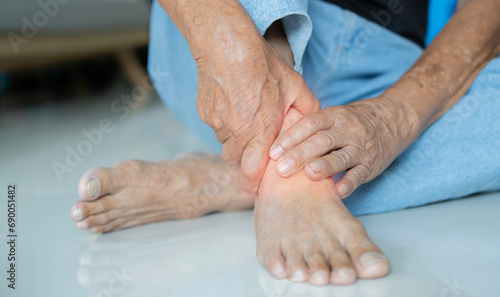 Senior man suffering for feet pain sitting on floor at home. Foot pain photo