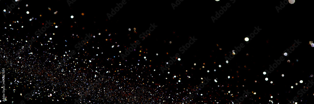 Glittering particles against a pitch-black background resembling a distant galaxy or the festive sprinkling of confetti in a dark night sky. Banner size