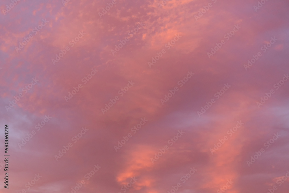 Warm hues adorn the sky as evening clouds reflect the setting sun's glow. Copy space background.