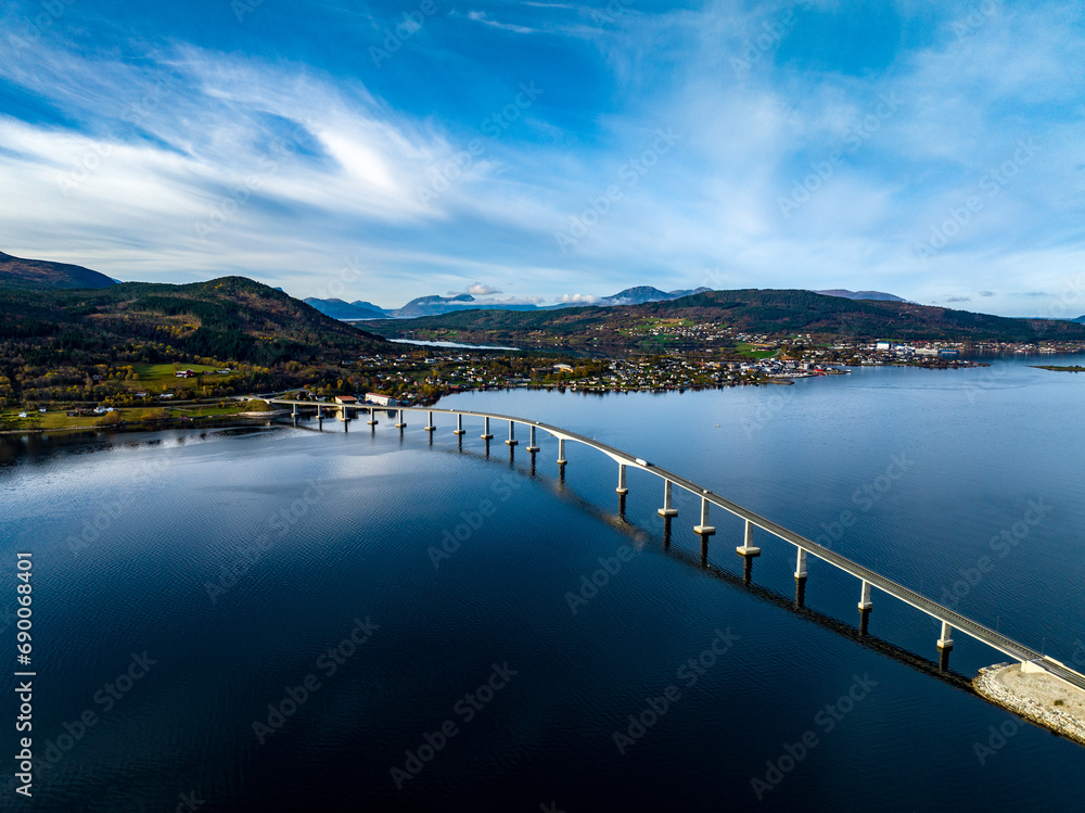 aerial view of Tresfjord Bridge with mountains on background with reflections on water in norway