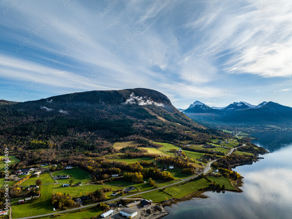 scenic aerial view over a road on the shore of norwegian Tresfjord with clouds in the mountains on background