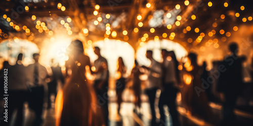 Blurred figures of people dancing in a hall with glowing bokeh lights, capturing the warm, festive atmosphere of a joyous celebration or elegant event photo