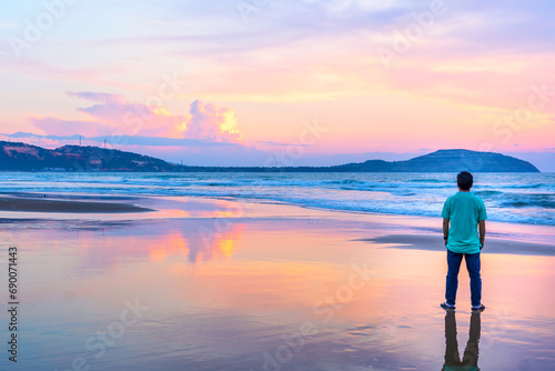 Silhouette of man on the beach looking at magical dramatic sunrise. The man standing on the sandy beach. Holidays on nature