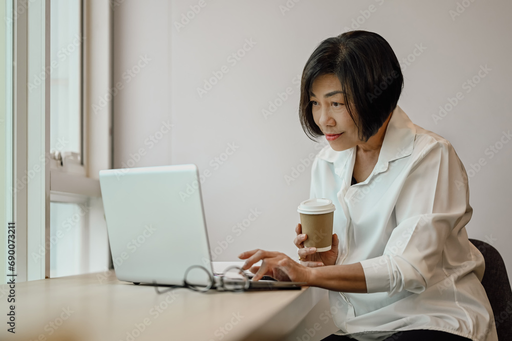 Experienced businesswoman typing on laptop working online and planning project at desk Experienced businesswoman typing on laptop working online and planning project at desk