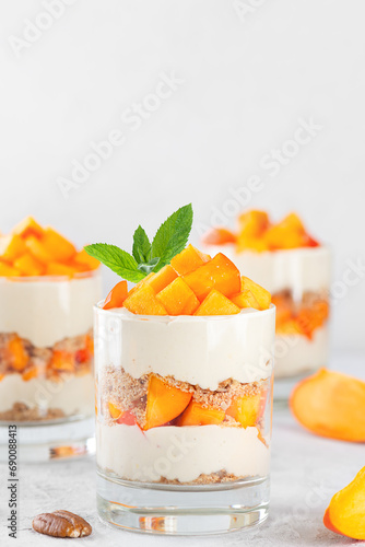 Parfait in a glasses with persimmon, mint, pecan, whipped coconut cream and biscuit. Vegan, sugar, gluten and lactose free.