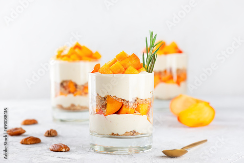 Parfait with persimmon, rosemary, pecan, whipped coconut cream and biscuit. Healthy food, vegan, sugar, gluten and lactose free.
