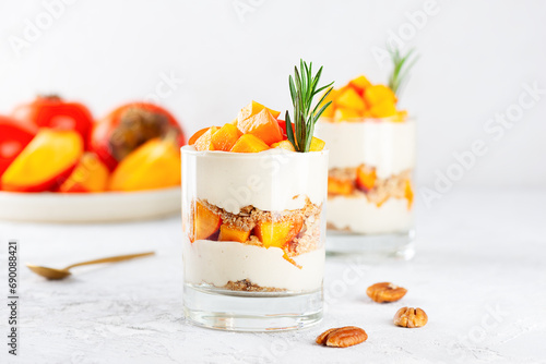 Trifle with persimmon, rosemary, pecan, whipped coconut cream and biscuit. Healthy food, vegan, sugar, gluten and lactose free.