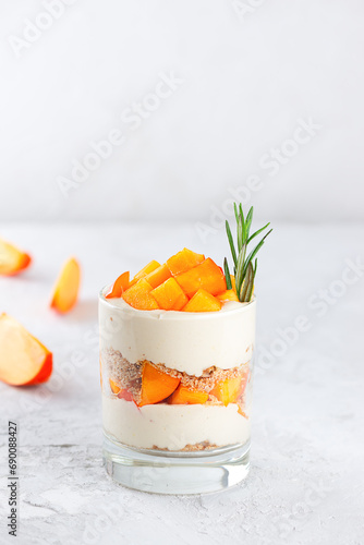 Dessert in a glass with persimmon, rosemary, pecan, whipped coconut cream and biscuit. Healthy food, vegan, sugar, gluten and lactose free.