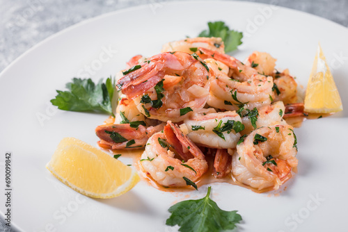 Fried Argentine shrimps with garlic and herbs on a white plate with lemon. 