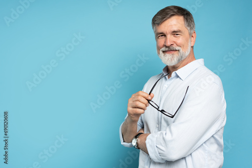 Slika na platnu Bearded middle-aged man wearing glasses posing over blue studio background