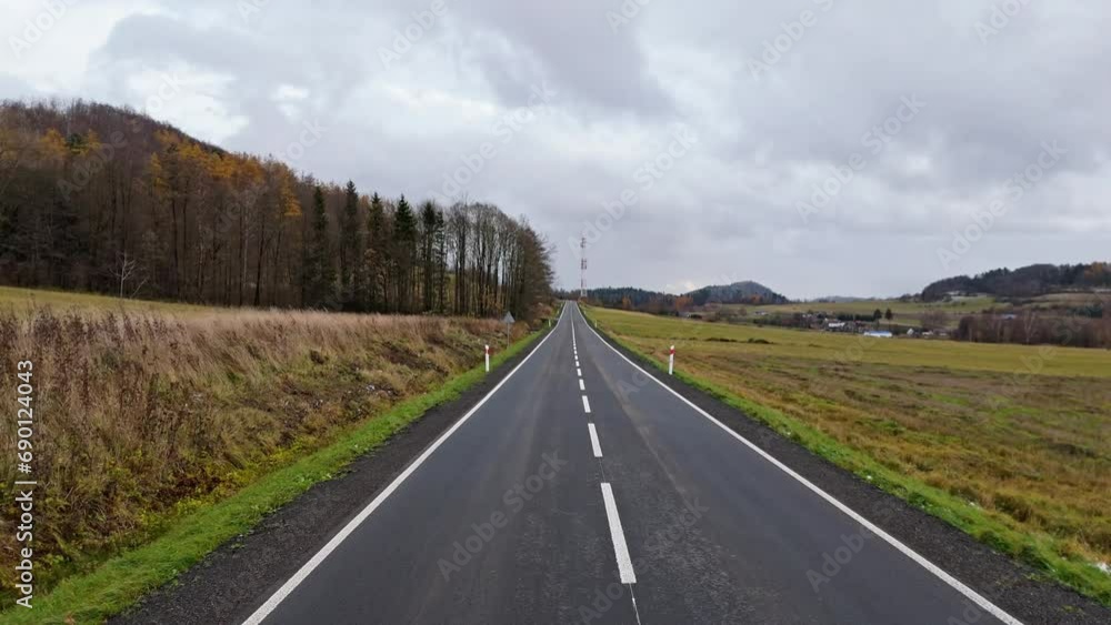 A drone's first-person view travels down an empty road, heading towards a cell tower on a gloomy autumn day. A drone's first-person view travels down an empty road, heading towards a cell tower on a gloomy autumn day.