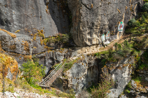 Landscape with Suspension Bridge over Bhote Kosi River during Three passes trekking in Sagarmatha national park, Nepal. A bridge with Guru Rinpoche images on rocks on the way to Thame.