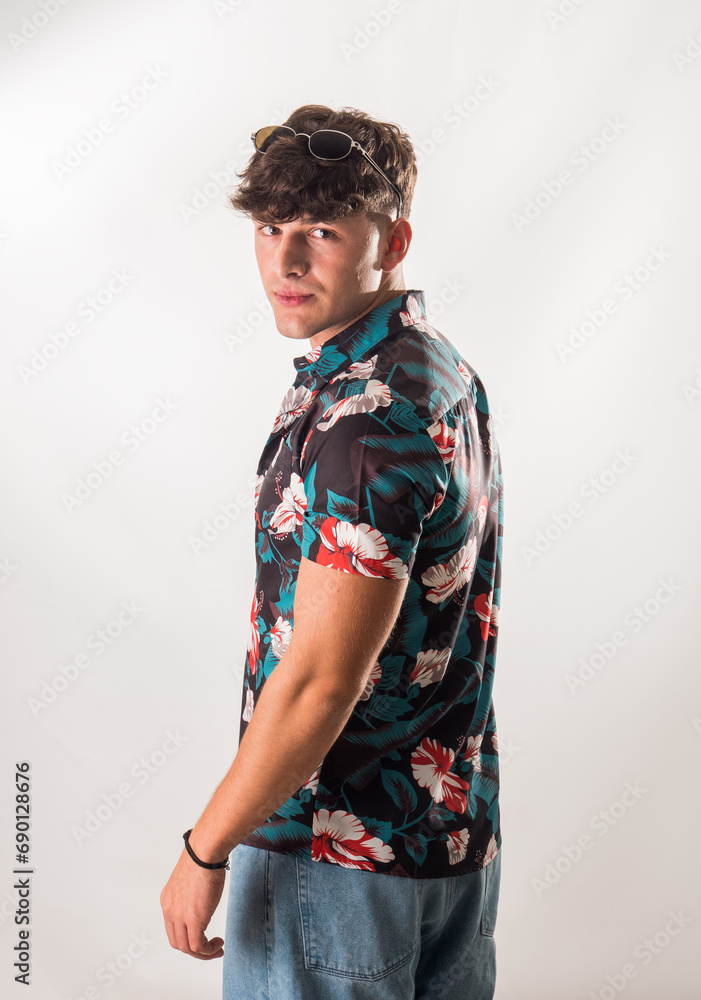 Attractive, muscular young man smiling, wearing open hawaian style shirt on white background