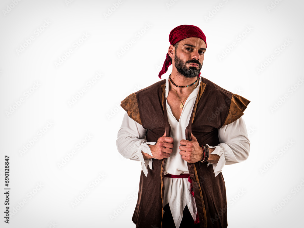 A muscular topless man with a red bandanna and pirate costume, standing isolated in front of a white background. A Brave Soul in Crimson: A Male Bodybuilder with a Red Bandanna Standing Proudly Before