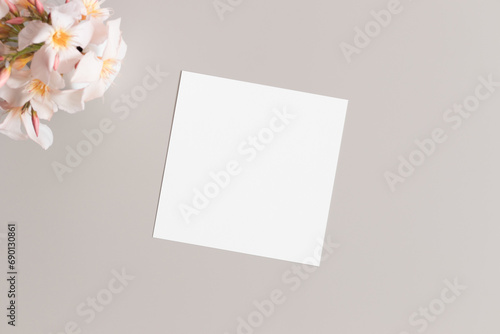 Square invitation card mockup with a oleander on the beige table.