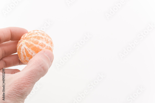 immagine con primo piano di mano che regge un frutto di mandarino pelato, clementina, superficie superficie bianca a sfondo photo