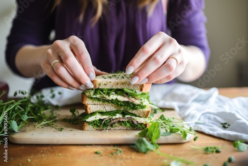 a girl layering fresh herbs on a half-finished sandwich