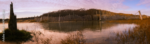 Flooded beach yard after winter rain in Cape Cod coastal village with rustic snow fens and bush hills in the water, Massachusetts, USA