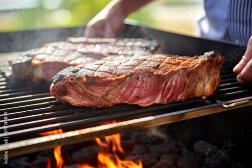 close image of a person checking the t-bone steak on grill photo