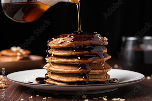 pouring maple syrup on a stack of vegan pancakes photo