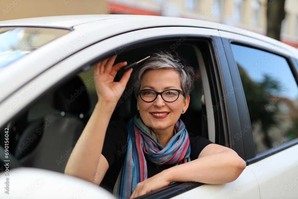 A happy and confident mature woman enjoys driving, embodying safety and joy on a summer journey. A happy and confident mature woman enjoys driving, embodying safety and joy on a summer journey.