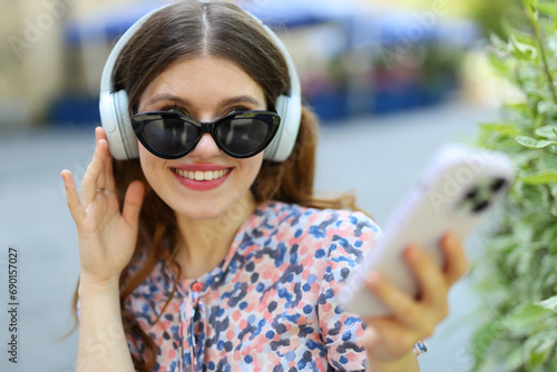 Young woman, immersed in music, enjoys the outdoors with style, showcasing beauty and modern lifestyle.