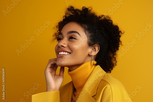 A chic Gen Z woman strikes a pose, fully exposing her ear, set against a trendy mustard yellow background. photo