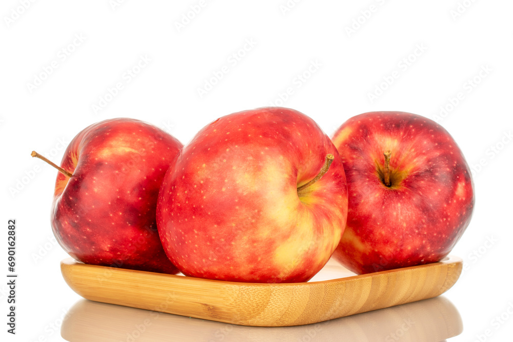 Three ripe juicy apples on a bamboo plate, macro, isolated on white background. Three ripe juicy apples on a bamboo plate, macro, isolated on white background.