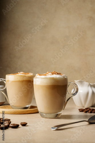 Fototapeta Naklejka Na Ścianę i Meble -  Two glass cups with coffee drink, latte with milk foam and cinnamon 