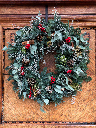 Christmas mood: festive christmasy themed winter natural wreath on a wooden door. Christmas wreath