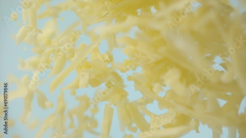 Heap grated cheddar cheese flying in slow motion close up. Shredded yellow parmesan cheese falling in macro. Ungraded raw ProRes footage for grading photo
