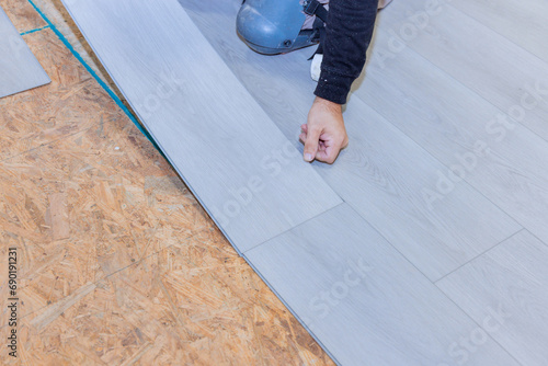 Worker installs vinyl laminate flooring in new residence