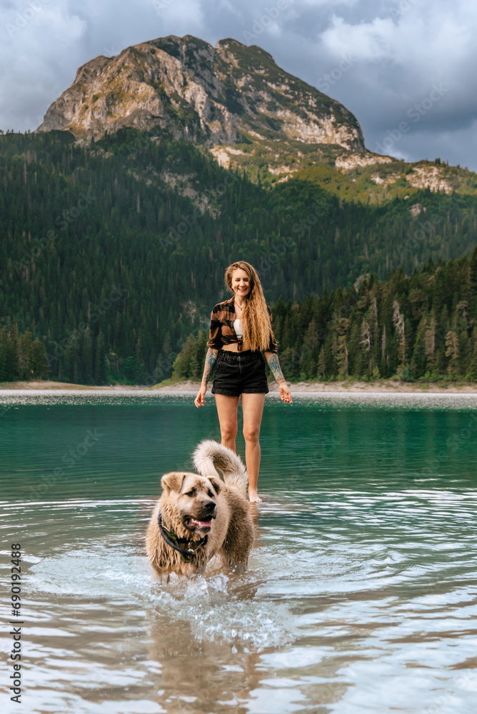 Woman Playing with Shepherd Dog in Mountain Lake