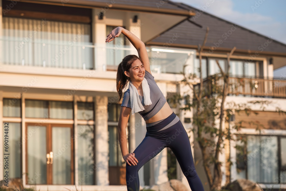 Young Asian woman exercising before a fitness session at the park in front of her house. Young healthy woman warming up outdoors She was stretching her arms and looking away. Young Asian woman exercising before a fitness session at the park in front of her house. Young healthy woman warming up outdoors She was stretching her arms and looking away.
