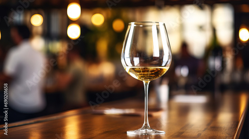 close up of a glas of white wine with blurred Bartender and bar in the back with empty copy space © Uwe