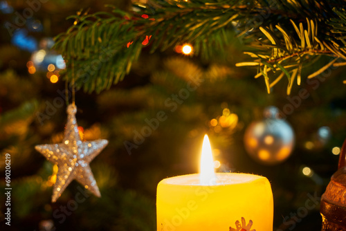 Candle flame and star-shaped Christmas decoration on the tree during Christmas